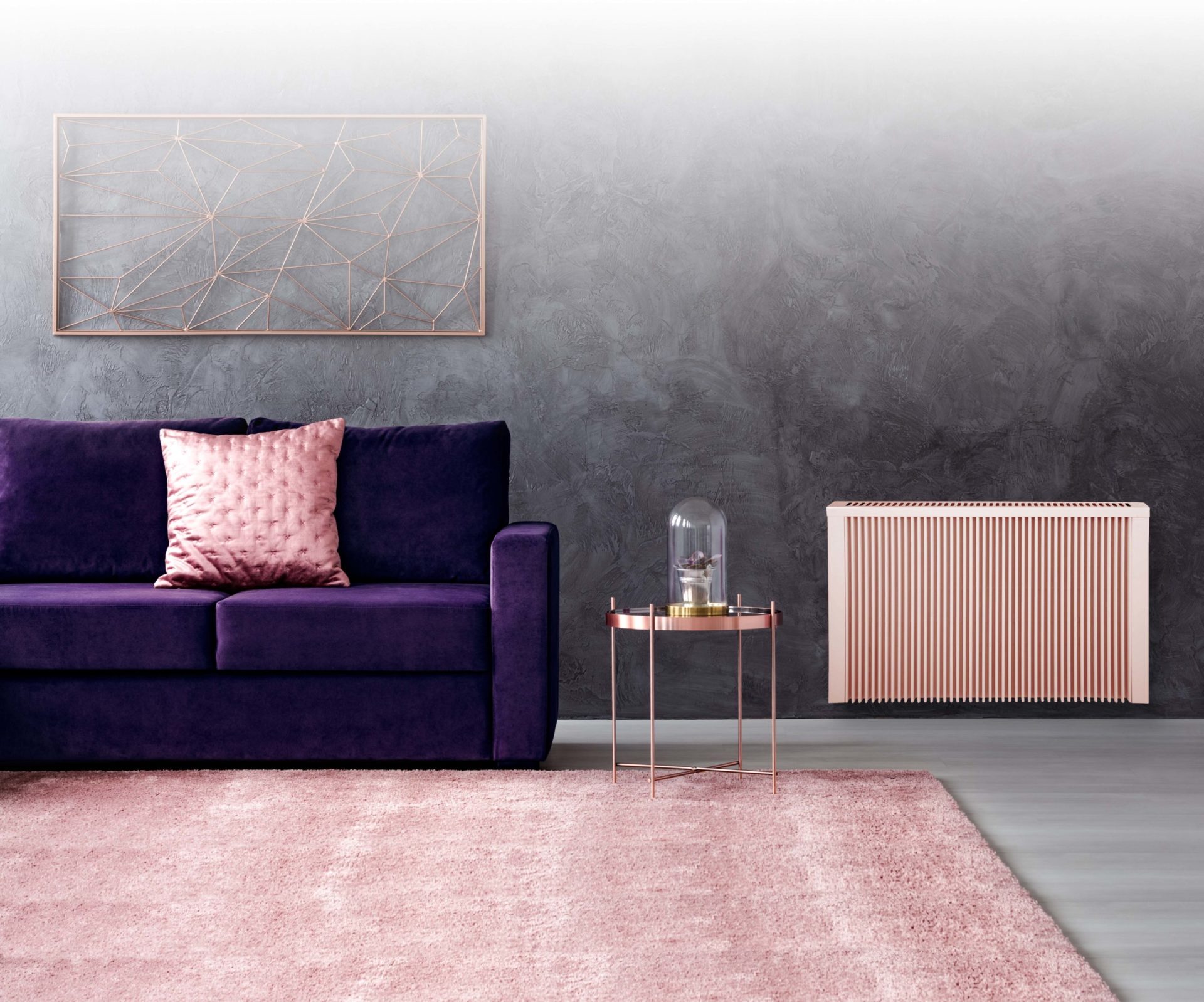 Shiny metal Sunflow electric radiator in a stylish living room with a purple sofa, salmon cushion, and carpet.